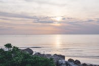 夕阳西下，海面宁静，海浪轻拍着崎岖的海岸线，营造出一片祥和的海景