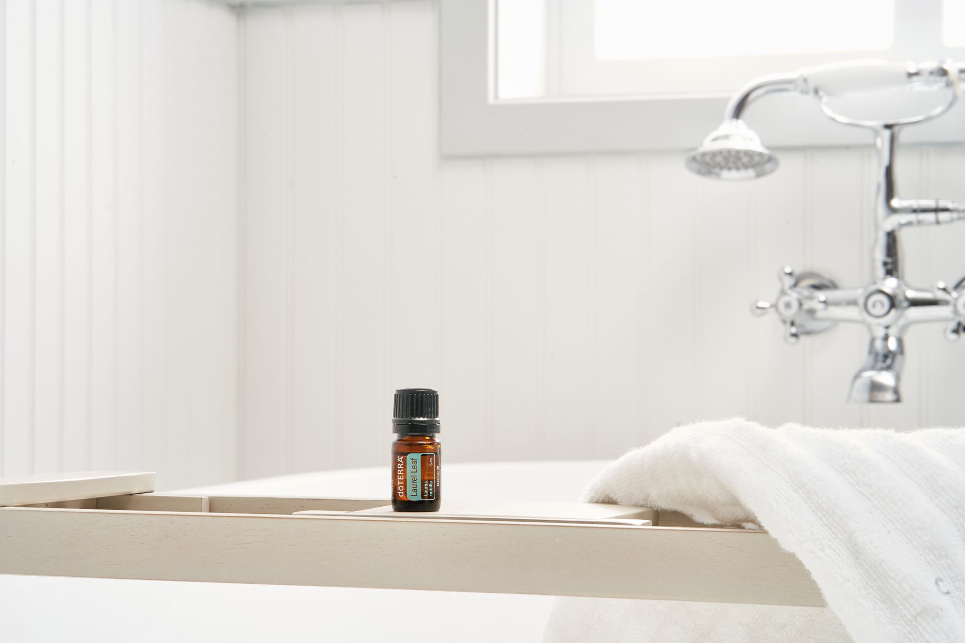 Serene bathroom setting featuring an essential oil bottle on a wooden tray with towel.