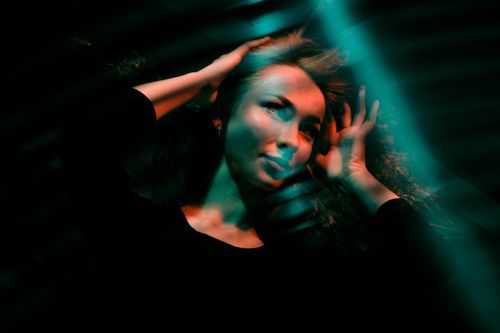 Free Artistic portrait of a young woman with creative green light effects, conveying a moody and dramatic atmosphere. Stock Photo