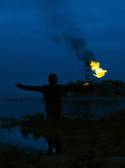 Silhouette of a Person Holding a Torch