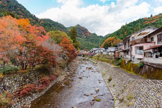 River Flowing Through a Town Surrounded by Forested Hills in Autumn