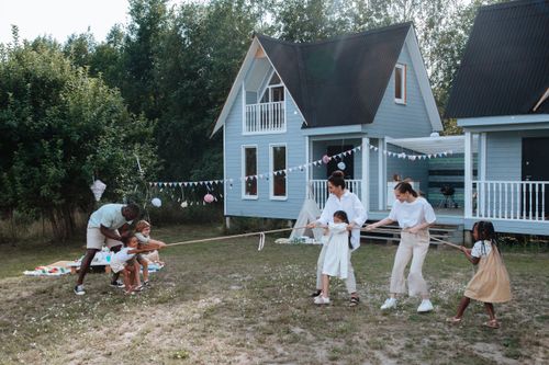 Free Happy family playing tug of war in front of cozy houses during a summer day. Stock Photo