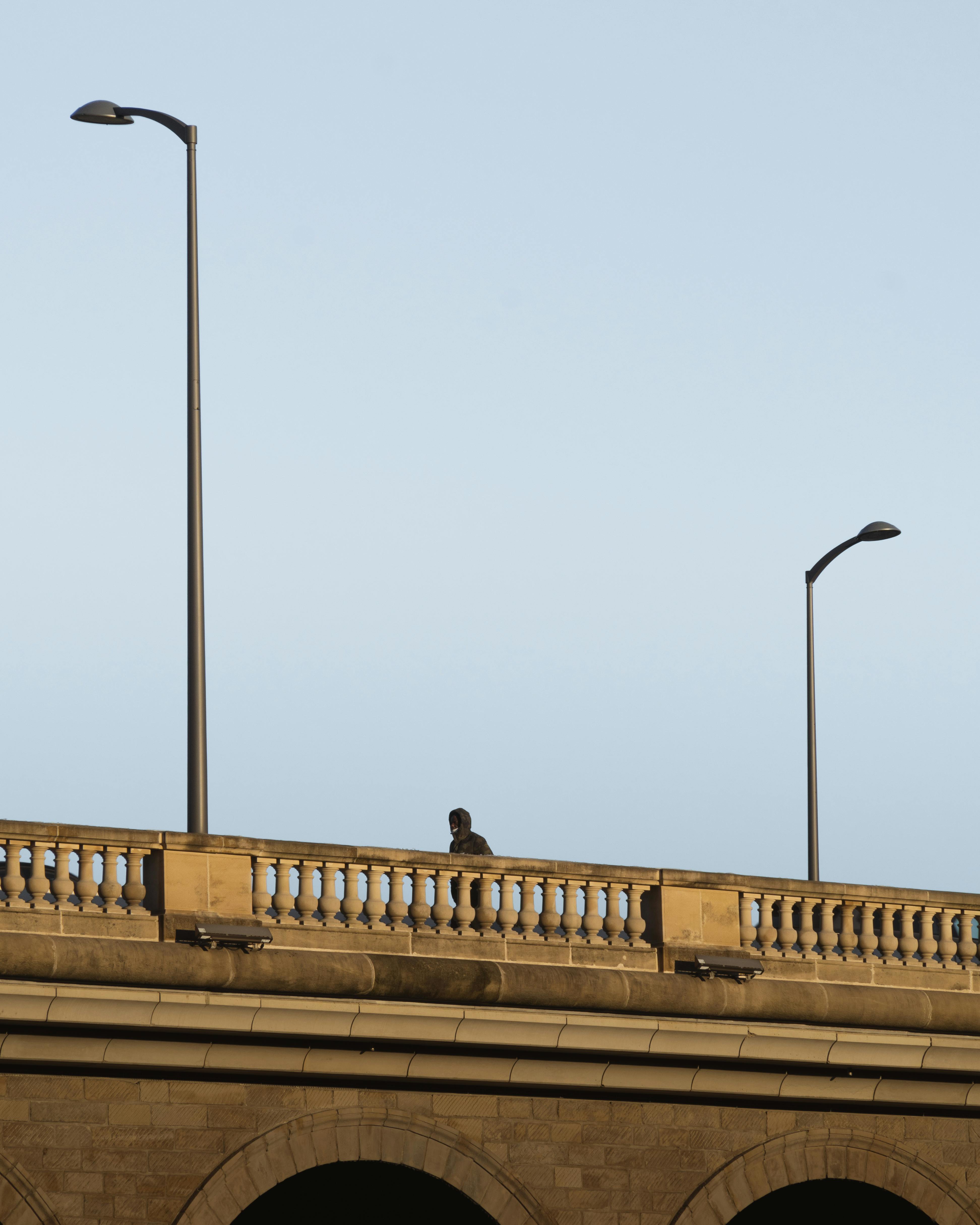 A lone pedestrian walks on an elegant stone bridge under clear skies in Luxembourg.