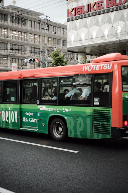 Free Green and red city bus driving past the Kisuke Box Amusement Complex. Stock Photo