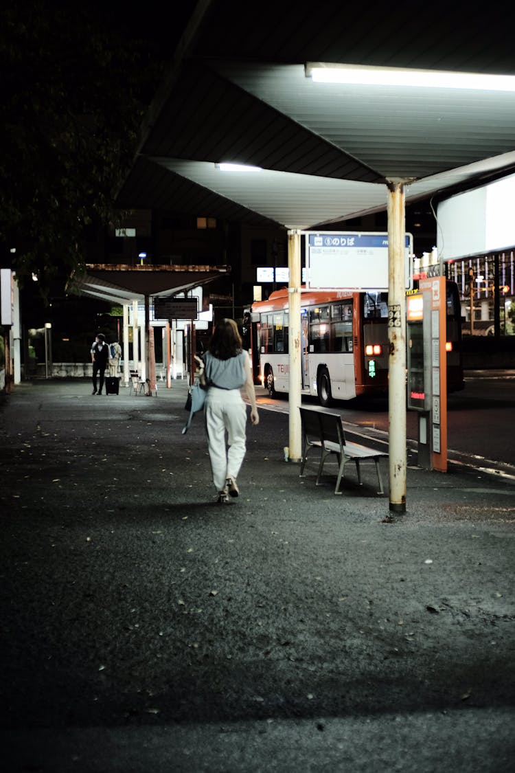 Woman Walking Through Bus Station At Night