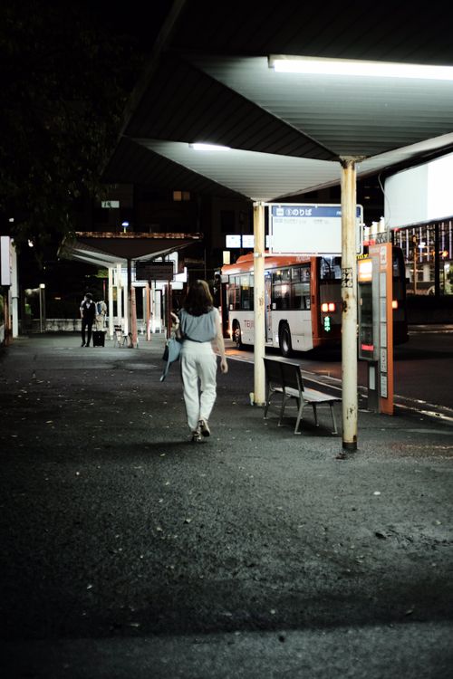 Free A woman walking through a dimly lit bus station at night, focused on travel. Stock Photo