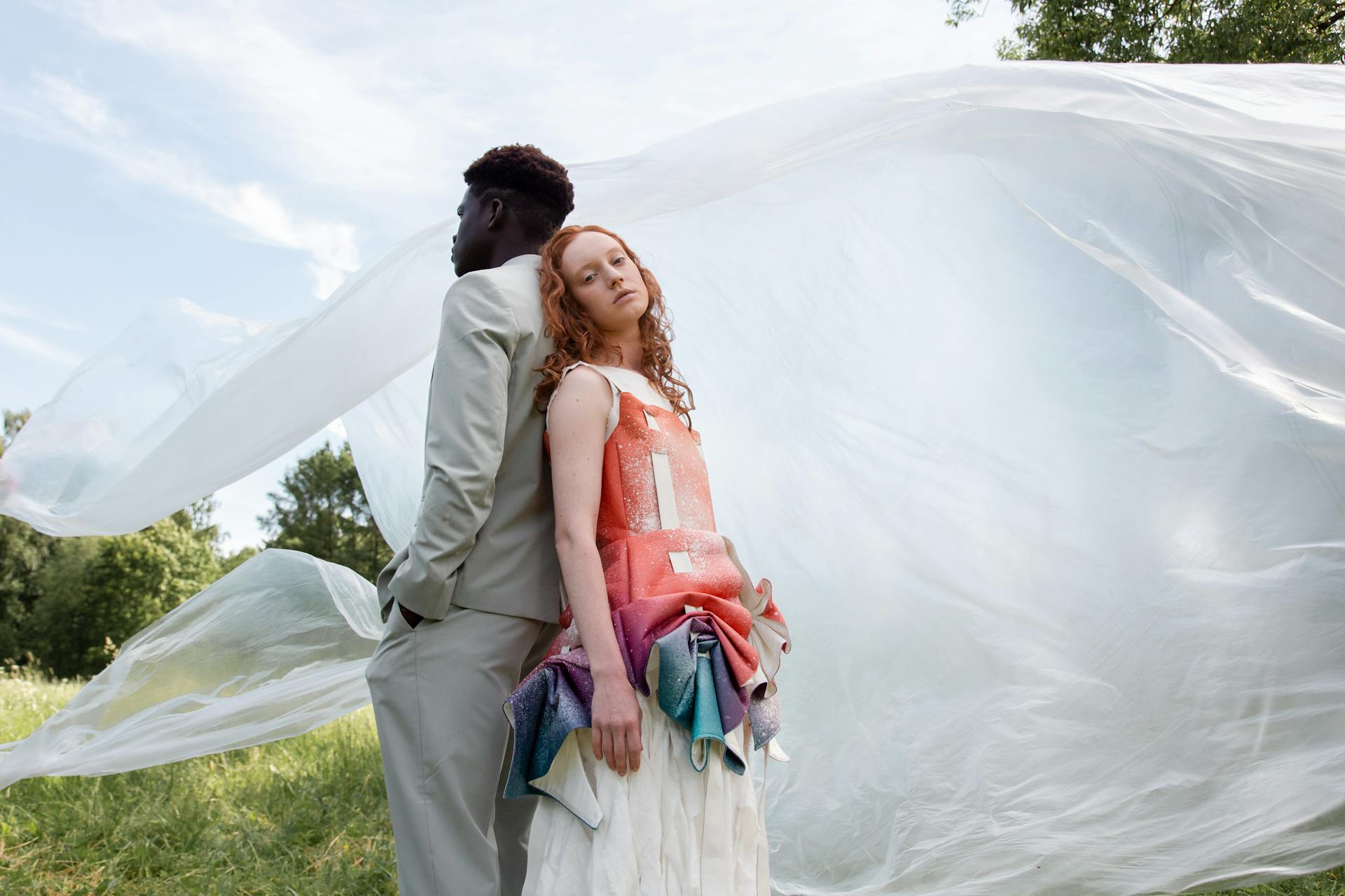 Man and Woman Standing on Green Grass Field with a Plastic Wrapper