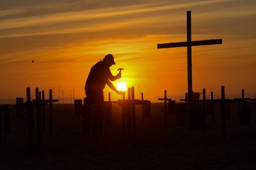 Free Dramatic silhouette of a man hammering at a grave as the sun sets in a Rio de Janeiro cemetery. Stock Photo