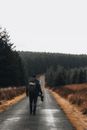 Alone Photographer with Backpack Walking Down Road to Dark Forest