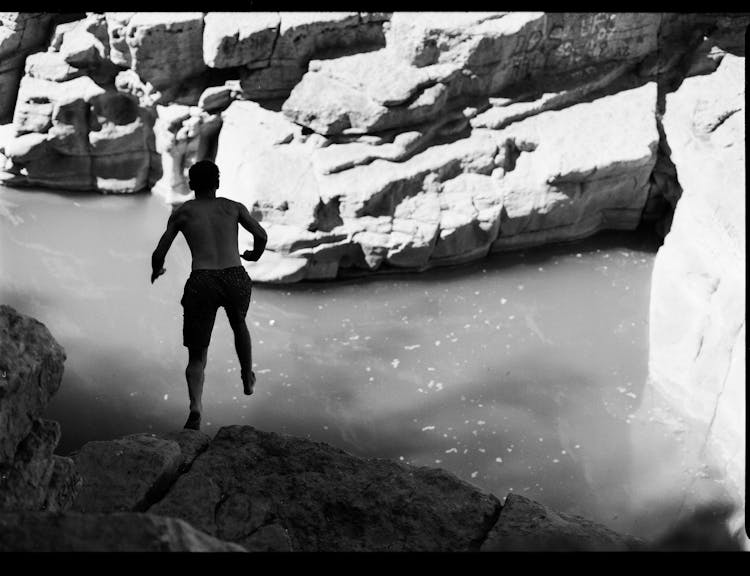 Man Jumping In Water From Rock