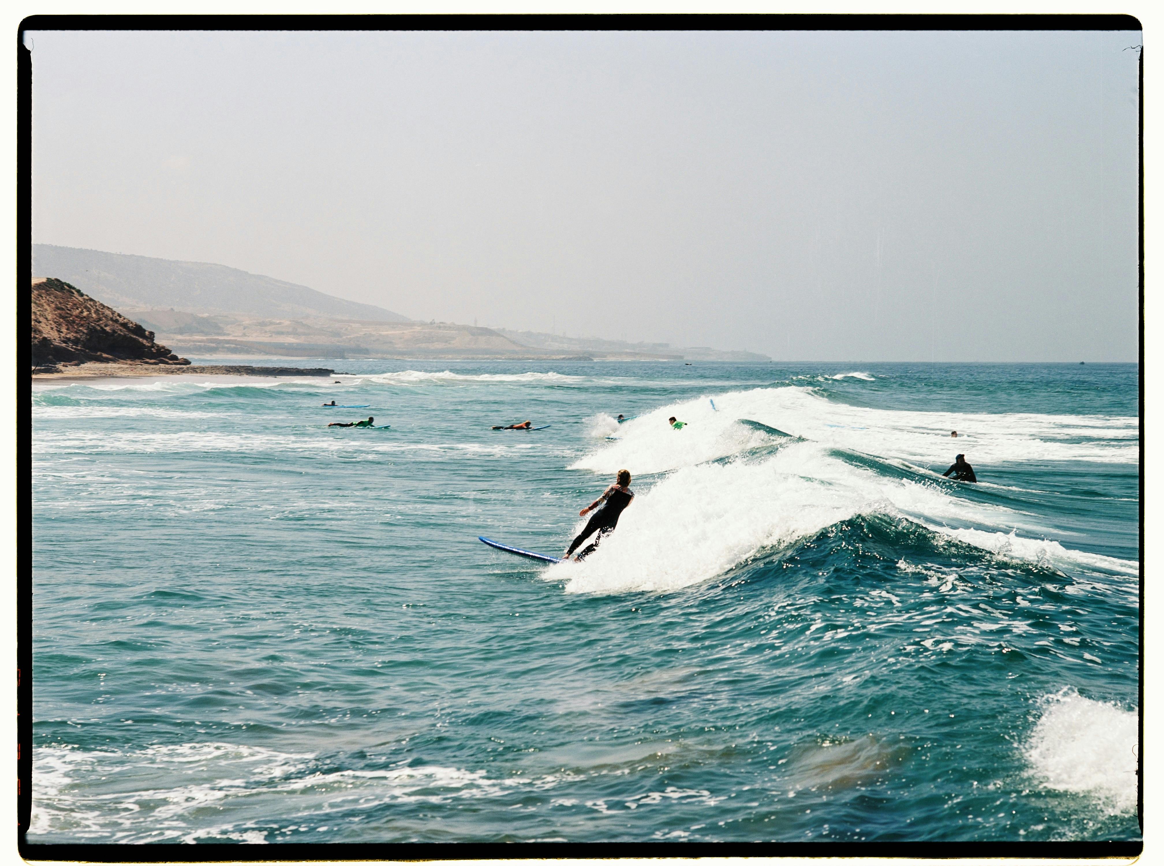 Surfers catching waves on the scenic Moroccan coast, perfect for outdoor adventure enthusiasts.