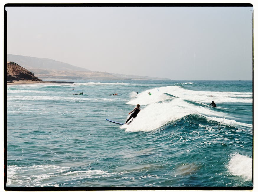Surfers catching waves on the scenic Moroccan coast, perfect for outdoor adventure enthusiasts.