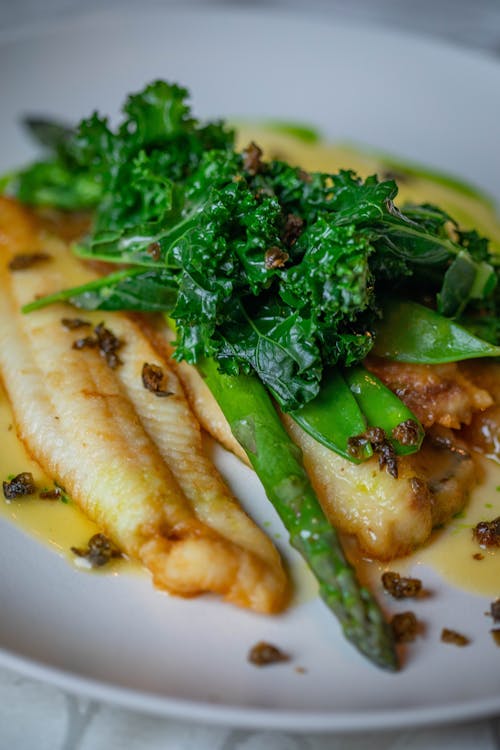 Roast Fish Fillets with Asparagus and Parsley Leaves on Plate