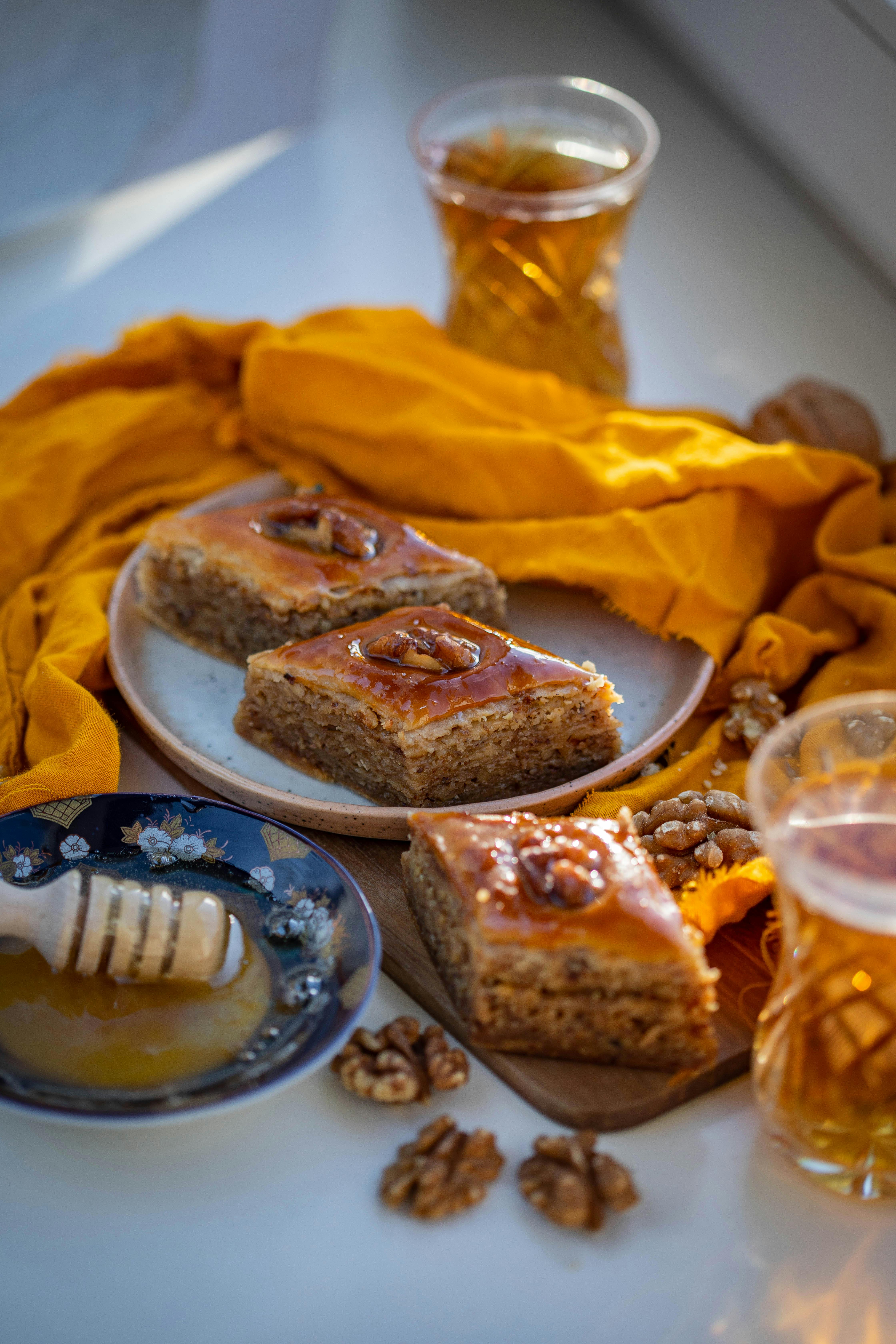 Close-up of baklava pieces with honey and walnuts, surrounded by orange textiles.