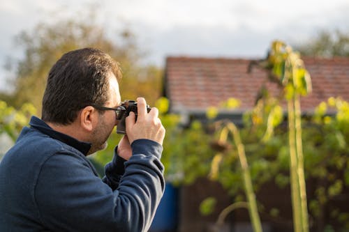 Selective Focus Photograph of a Man Using a Black Camera