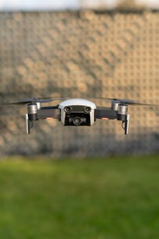Drone in mid-flight against blurred outdoor background, showcasing technology.