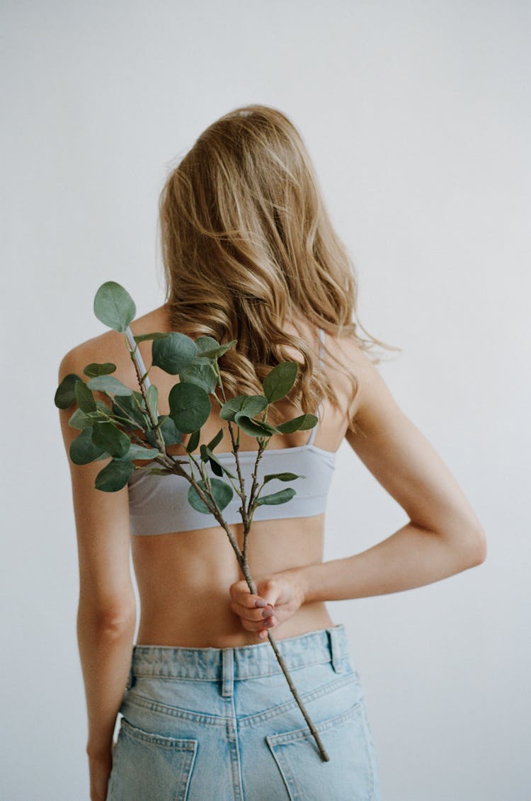 Rear View Of Woman Holding Flowers Behind Back