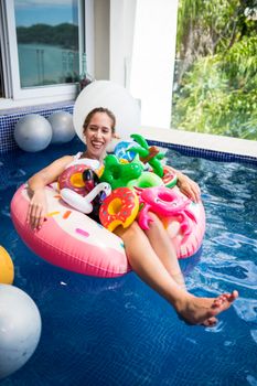 A woman smiling while lounging on a colorful inflatable in an outdoor pool.
