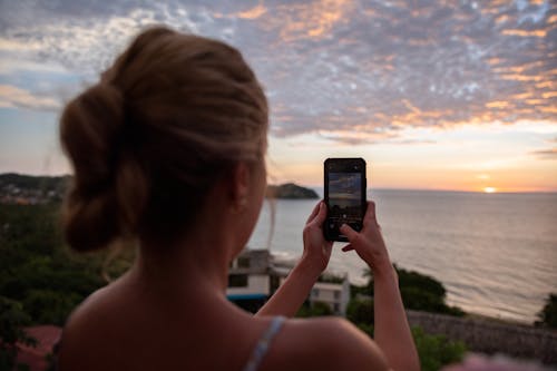 Woman Taking Picture of Sunrise