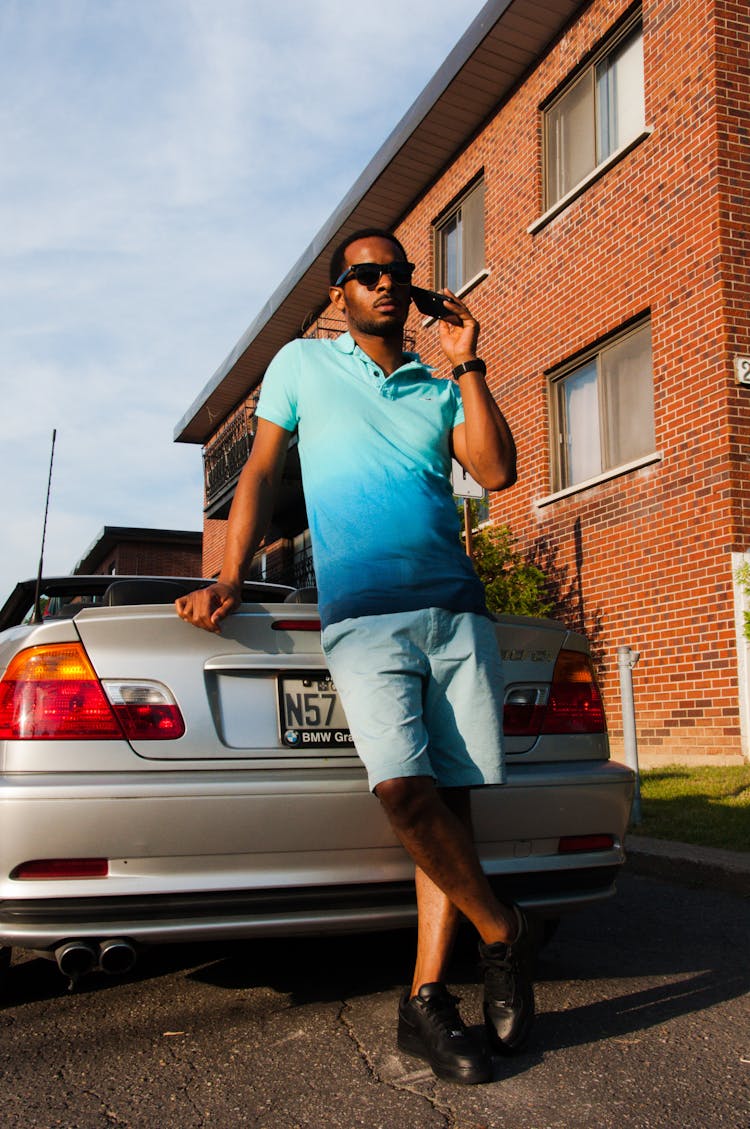 Man Leaning On The Back Of The Car While Having A Phone Call