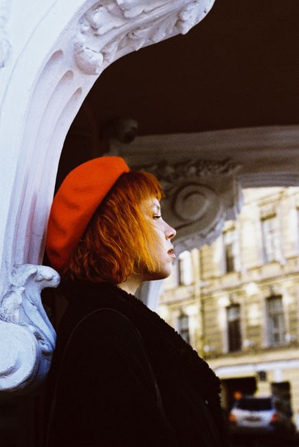 Artistic side view portrait of a woman in a red beret in Saint Petersburg.