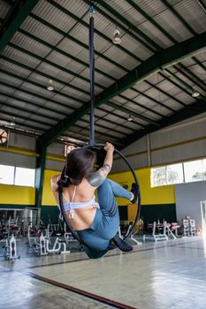 Woman performing aerial hoop exercise in a gym.