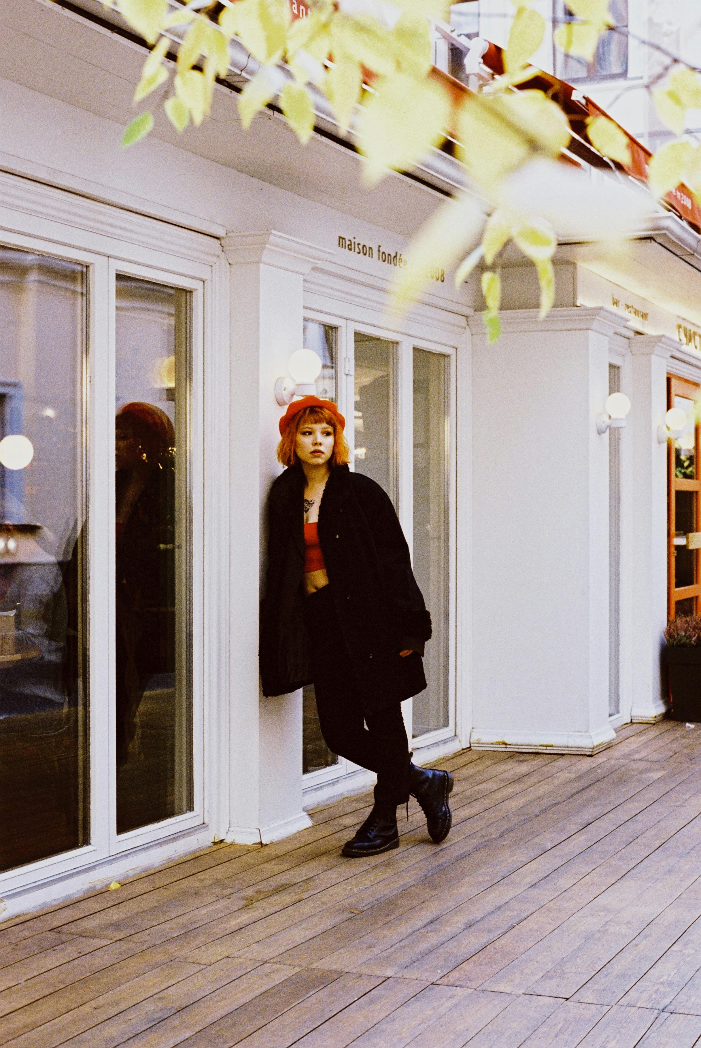 Fashionable woman with vibrant hair posing in urban setting with autumn vibe.