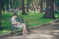 一位女士喜欢在树木繁茂的公园长椅上读书