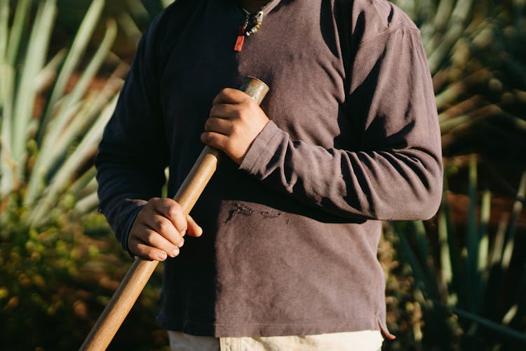 A Person Holding A Wooden Rod