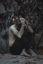 Portrait of Huddled Shirtless Man Holding Flowers