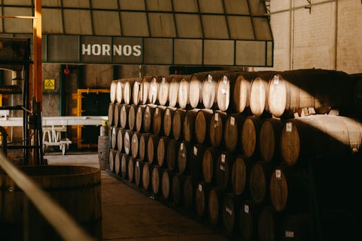 Wooden barrels aging tequila in a traditional Mexican distillery hall.