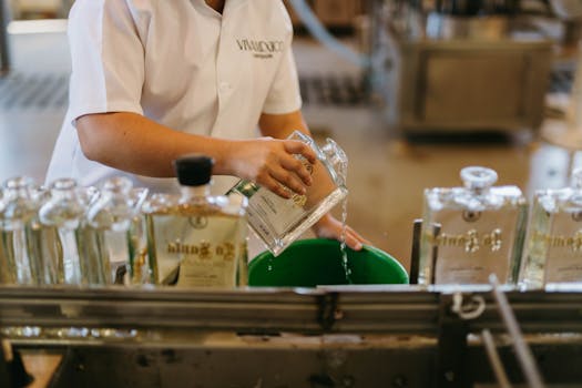 Hands pouring tequila into bottles in a Mexican distillery setting.