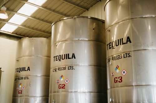 Free Large tequila storage tanks inside a Mexican distillery with visible capacity markings. Stock Photo
