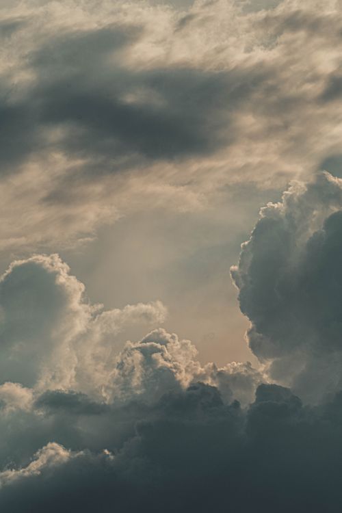 Free A dramatic view of a cloudscape with soft sunlight filtering through the clouds. Stock Photo
