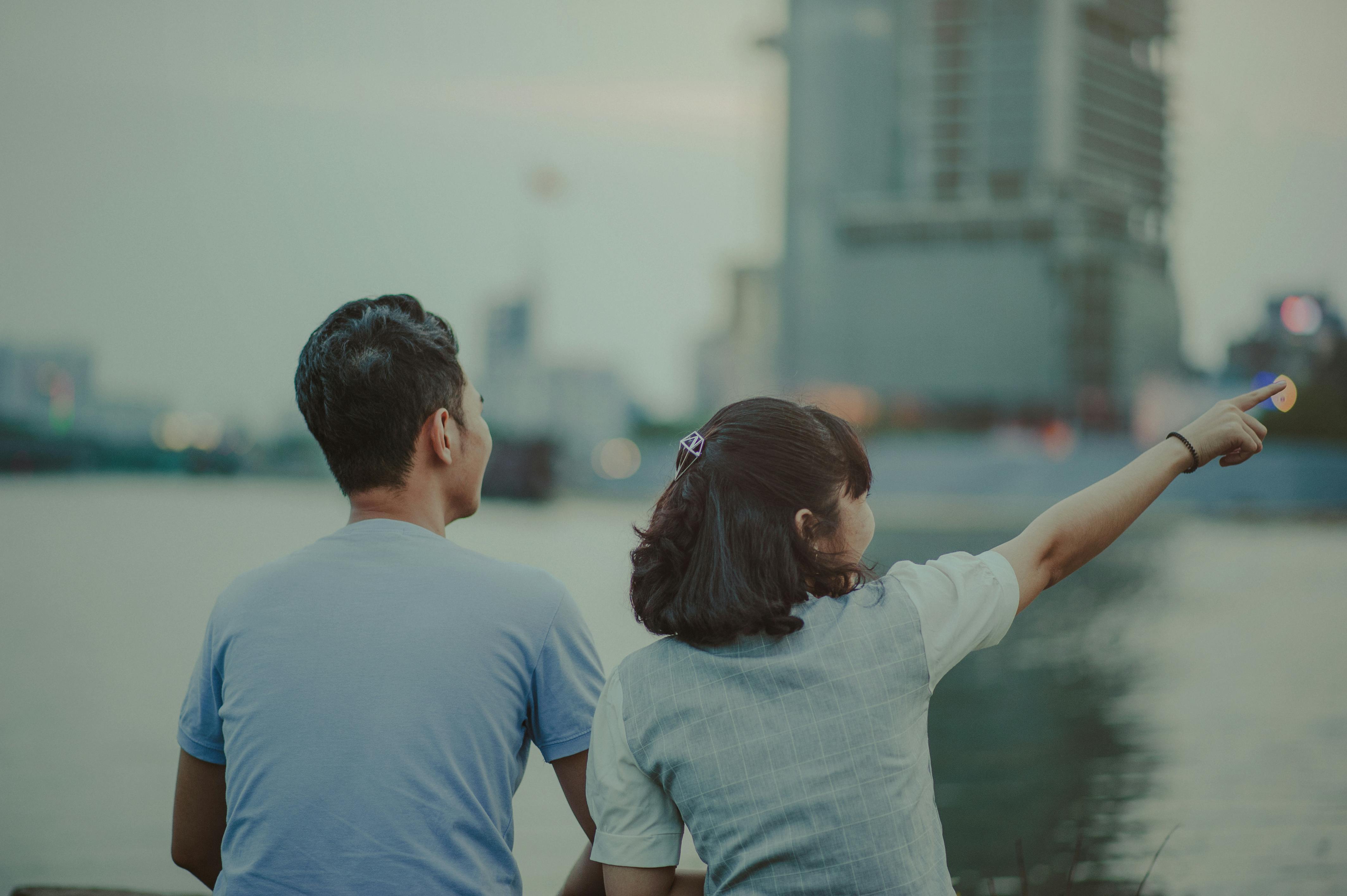 黄昏时分，一对夫妇坐在水边，指着城市天际线