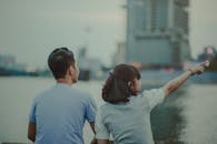 黄昏时分，一对夫妇坐在水边，指着城市天际线