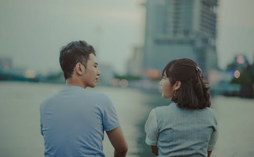 Man and Woman Facing Body of Water and Building