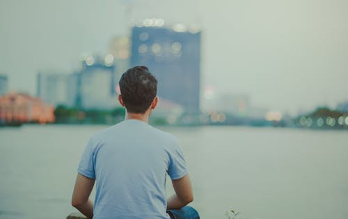 穿蓝色衬衫的男人坐在高层建筑上看的照片