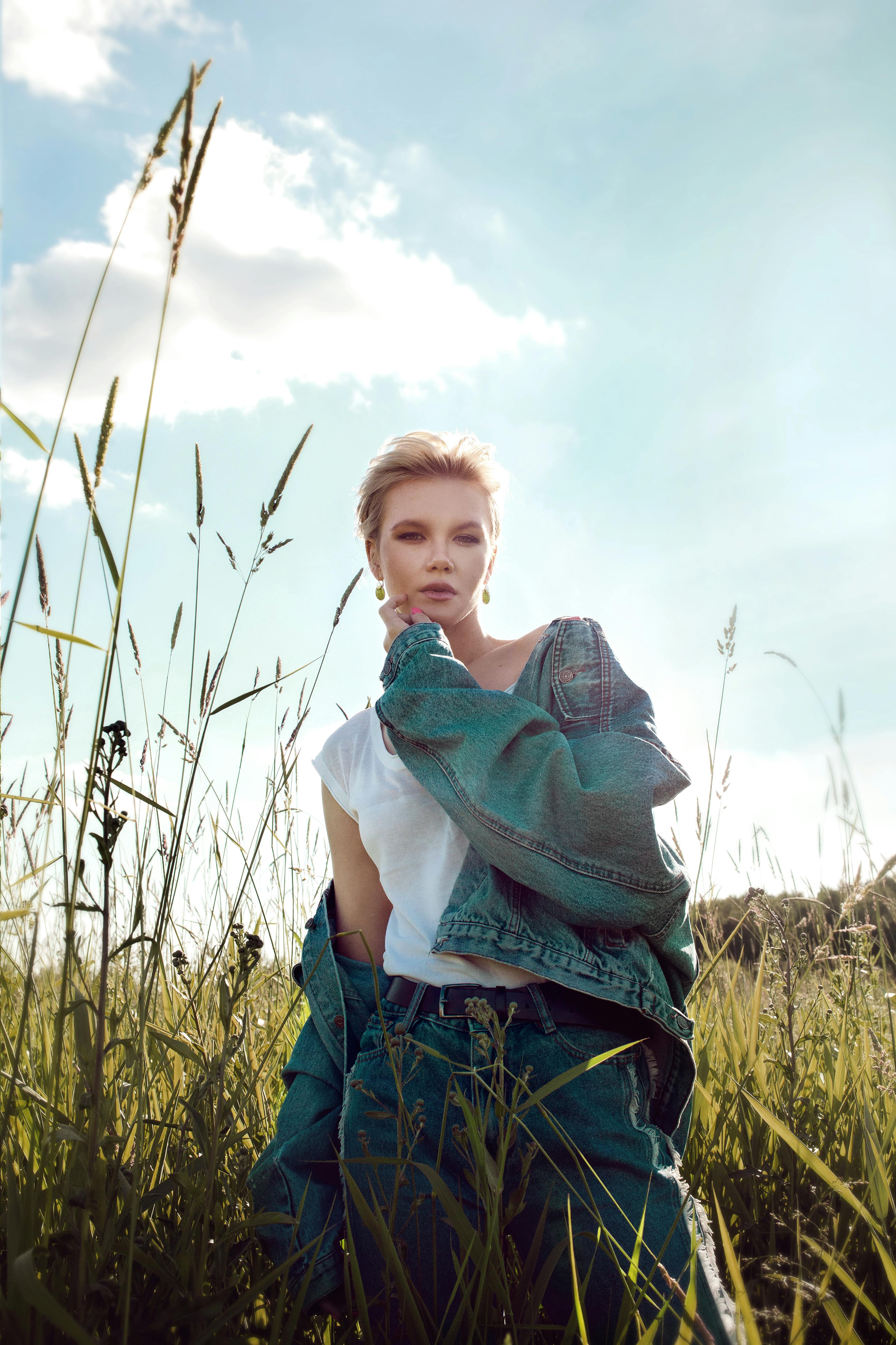 attractive blond woman in jeans wear standing in wild meadow