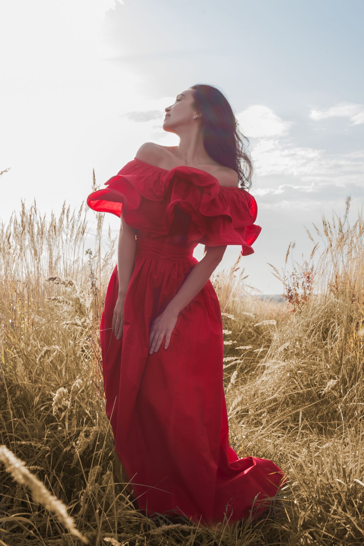 A woman in a red dress standing in a field — red at its most disarming