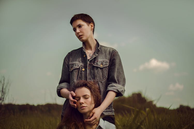 Woman With Short Hair Touching Head Of Her Sitting Sister