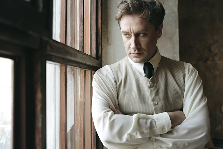 Blond Man In Beige Vest Looking Through Window