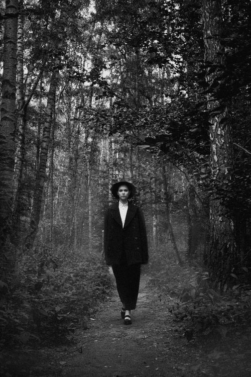 Free Black and white portrait of a well-dressed woman walking on a forest path. Stock Photo