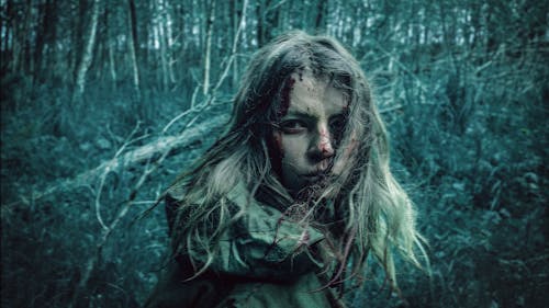 Blonde Girl Covered with Mud and Blood in Gloomy Forest