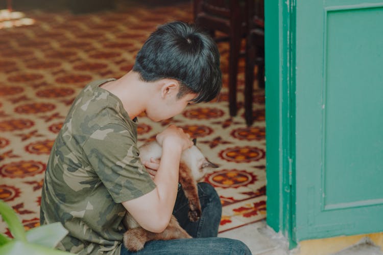 Photo Of Boy Wearing Camouflage Shirt Holding A Cat