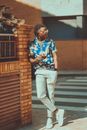 A Stylish Man Leaning on the Corner of a Brick Fence