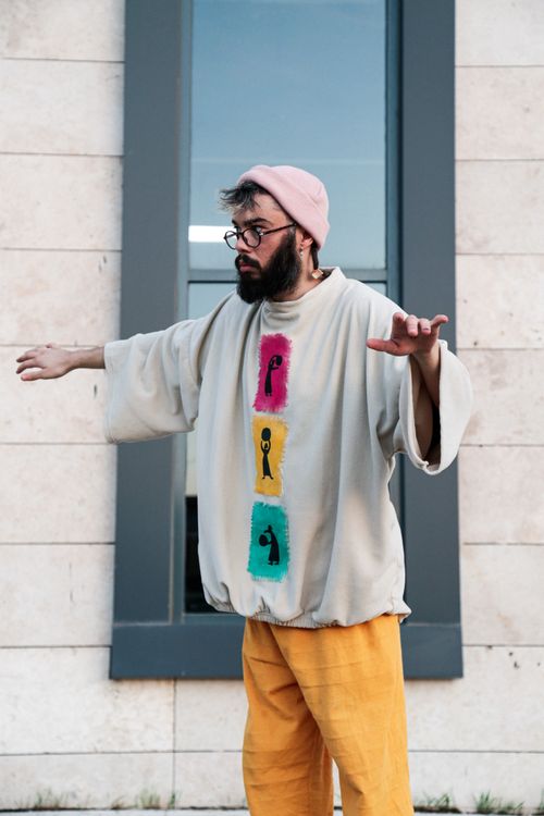 Free Bearded man in colorful shirt and knit hat posing dynamically outdoors. Stock Photo