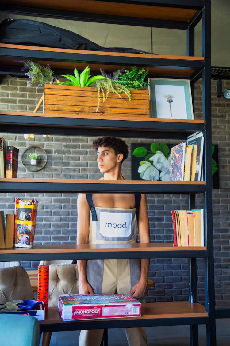 A Man In Overalls Standing Behind The Shelves