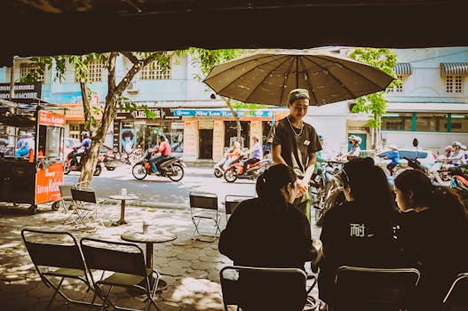 A bustling street cafe in Hanoi, Vietnam captures the lively atmosphere with people dining outdoors.