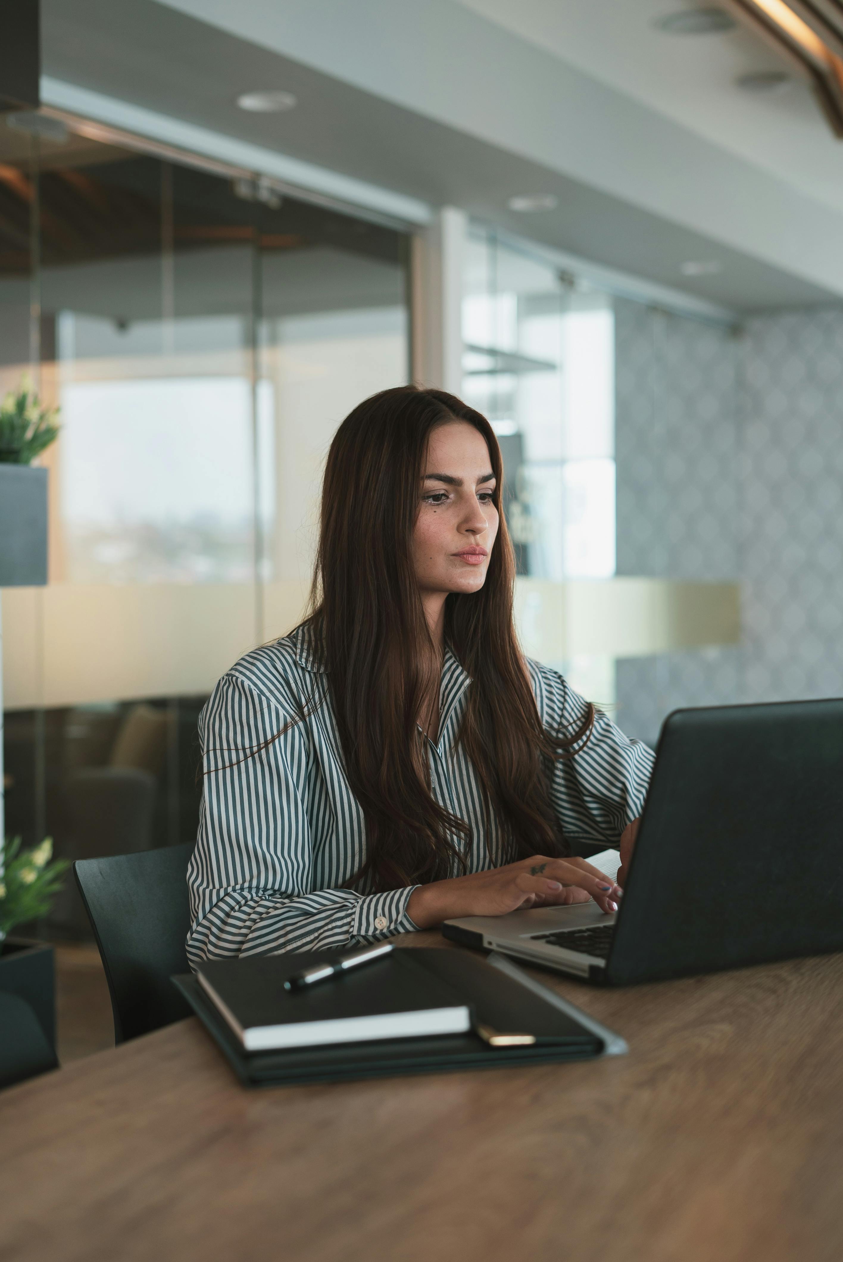 portrait of brown haired woman working on laptop in office